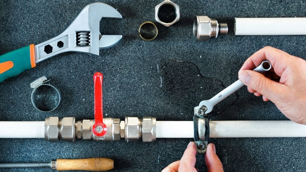 Plumber repairing a pipe valve with an adjustable wrench in Plantation