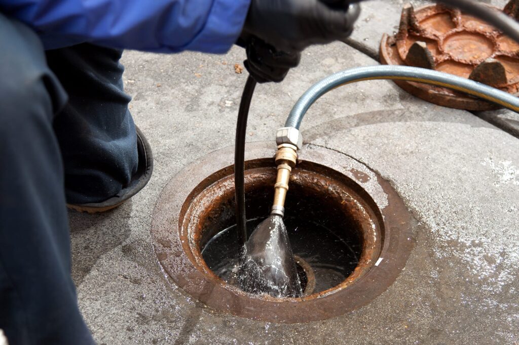 Plumber hydro jetting a sewer line through a manhole in Plantation