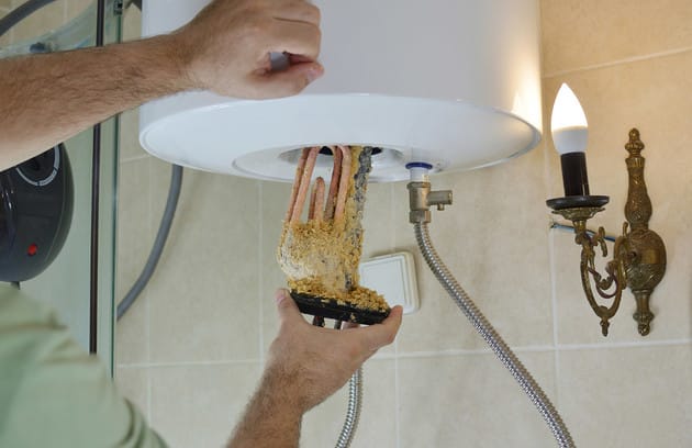 Technician removing mineral buildup from a water heater in Plantation