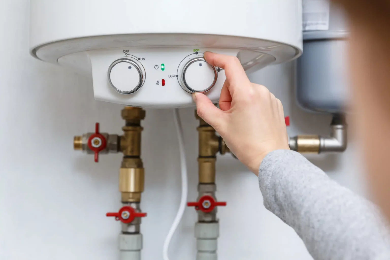 Homeowner adjusting the temperature controls on a water heater in Plantation